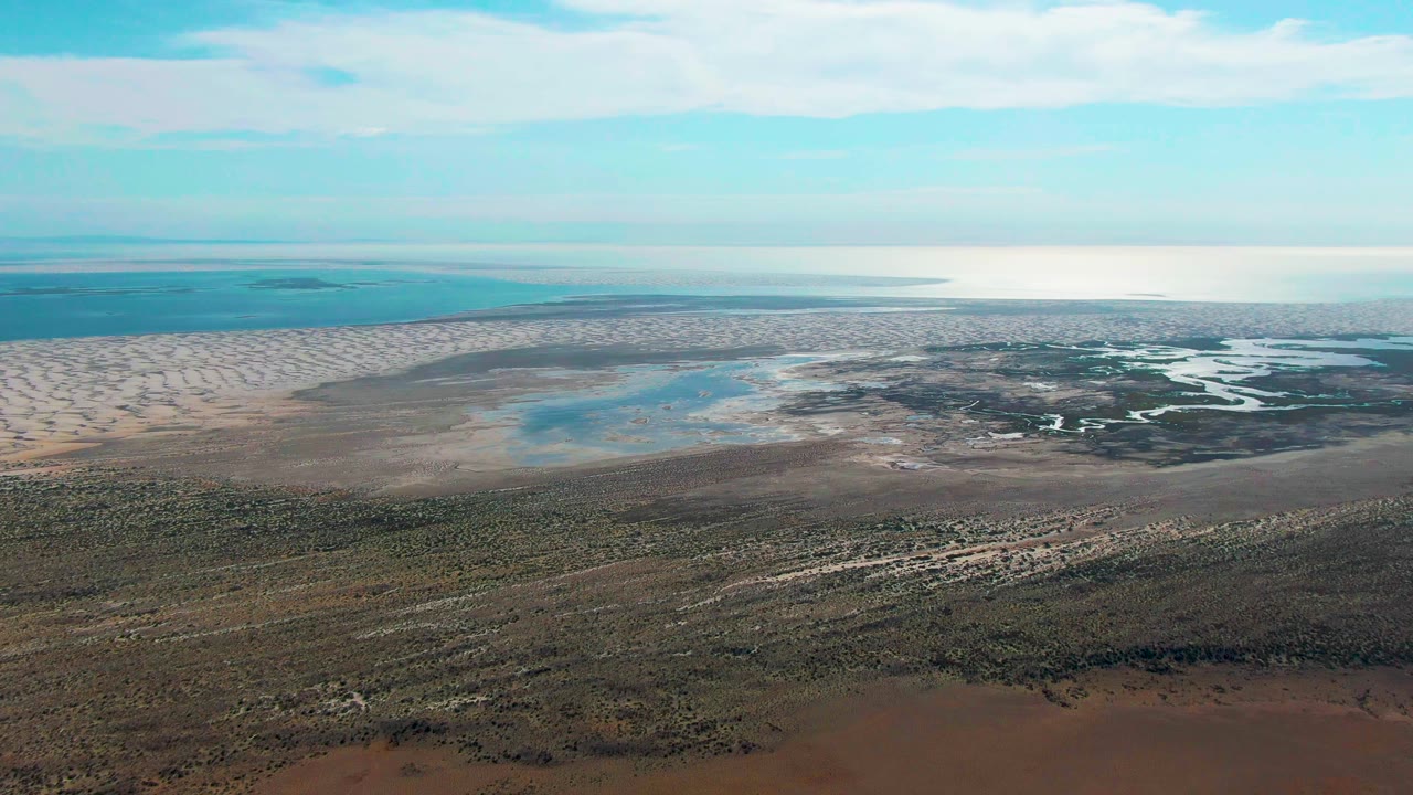 Aerial wetland view beneath a bright partly cloudy sky