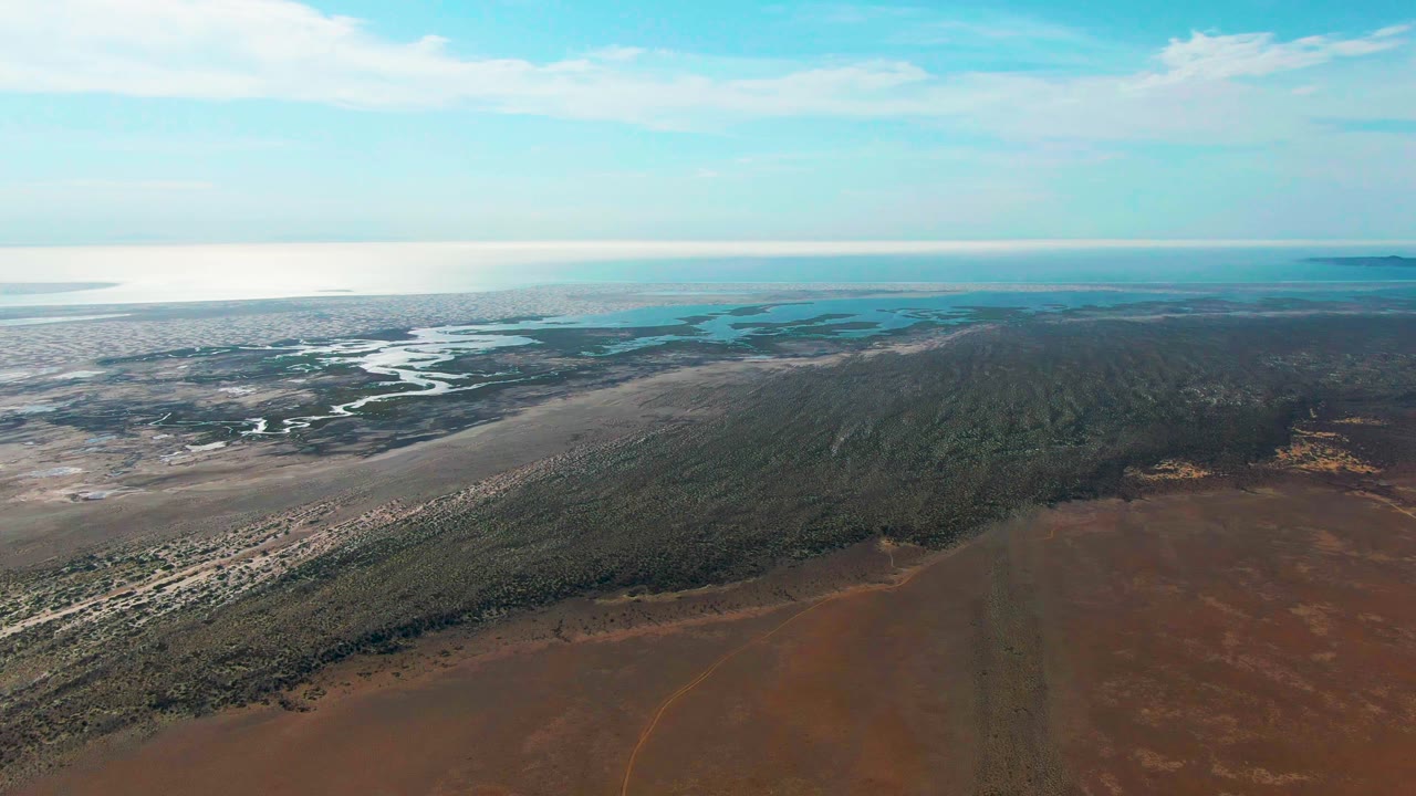 Aerial view of coastal wetlands, sandy shore, green vegetation, and brown land