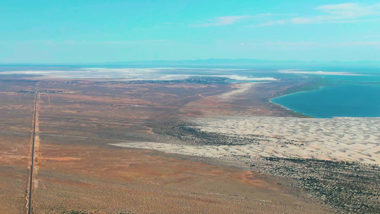 Aerial view of desert road, salt flats, and blue lake
