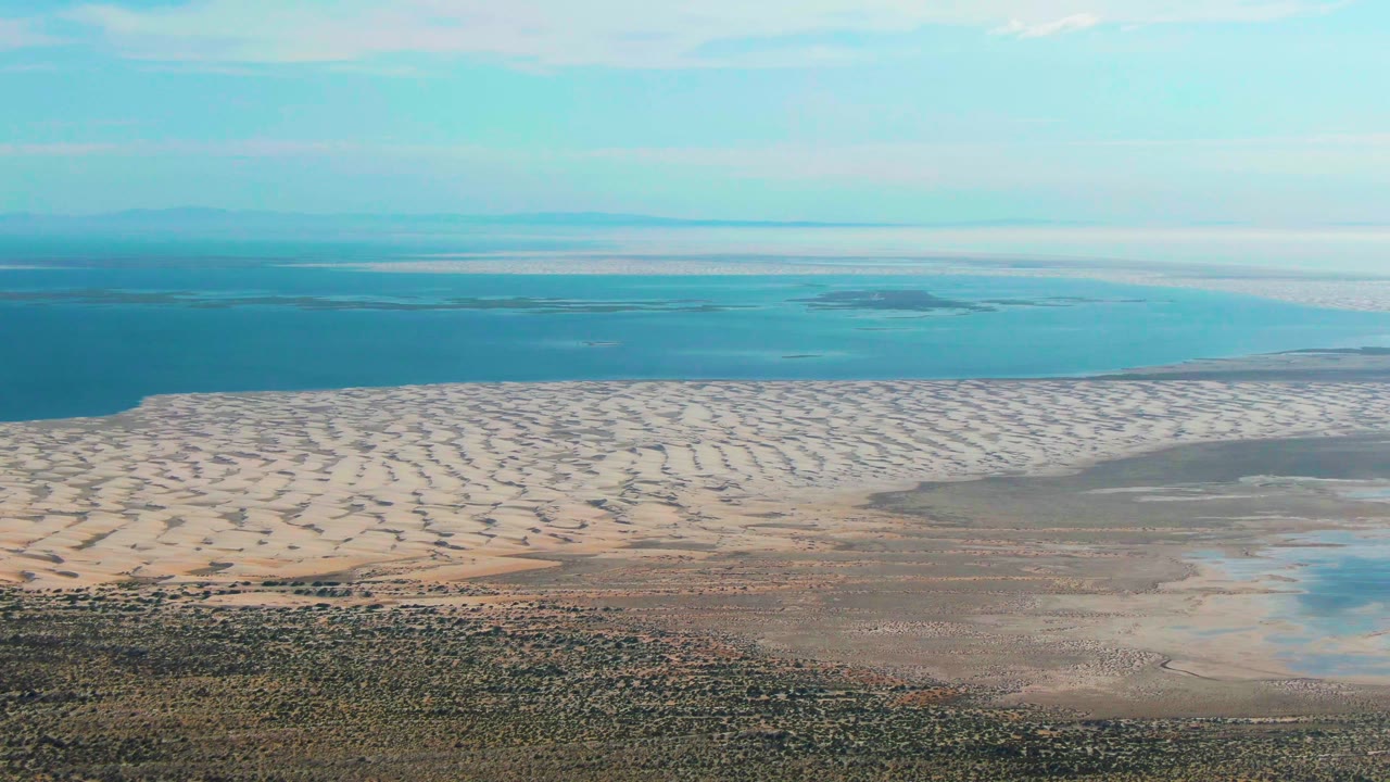 Aerial coastal dunes with shallow flats and ocean beyond.