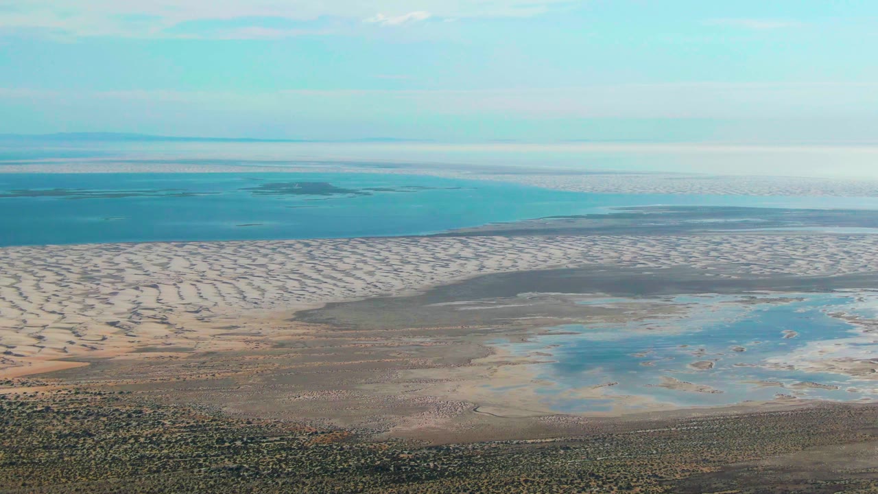 Aerial coastal flats with circular shore patterns and shallow water pools.