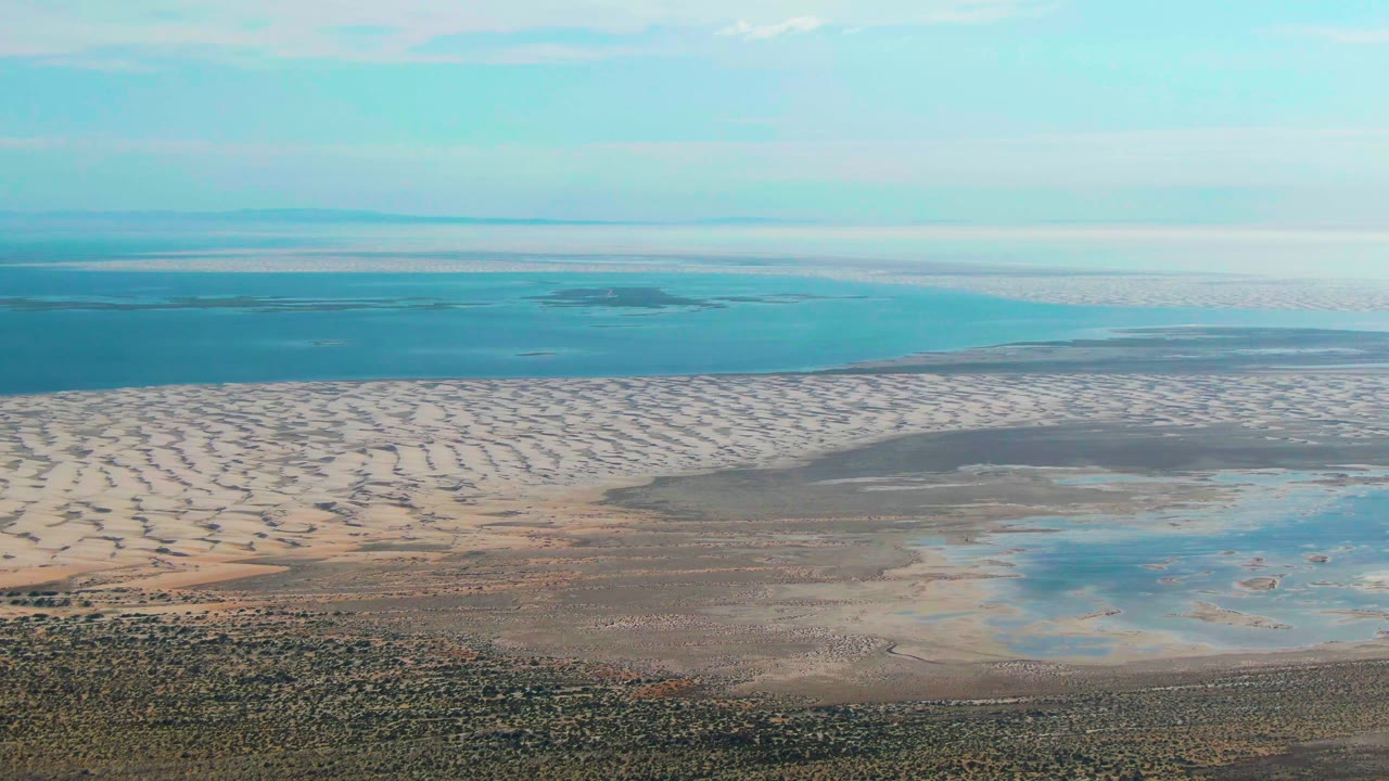 Aerial frame of dunes, tidal flats, wetlands, and distant ocean.