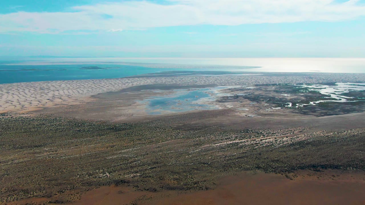 Aerial view of coastal dunes, tidal flats, shallow pools, and scrubland.