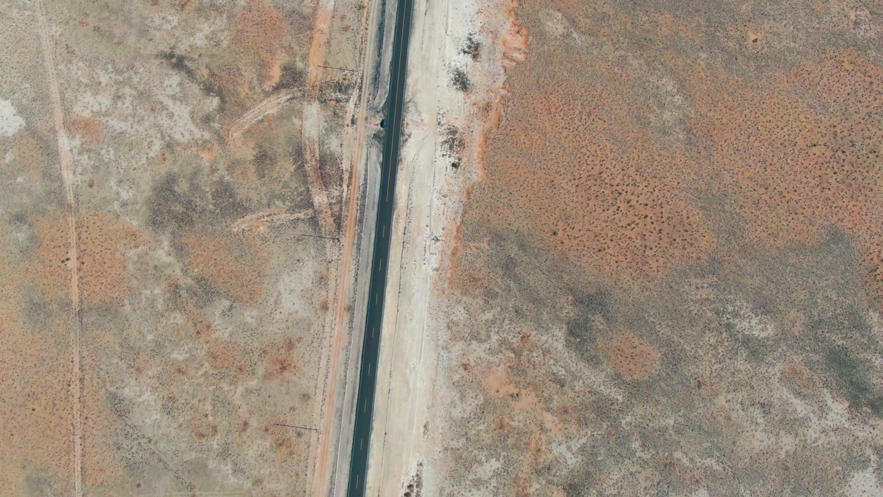 Aerial desert road with light traffic and open land