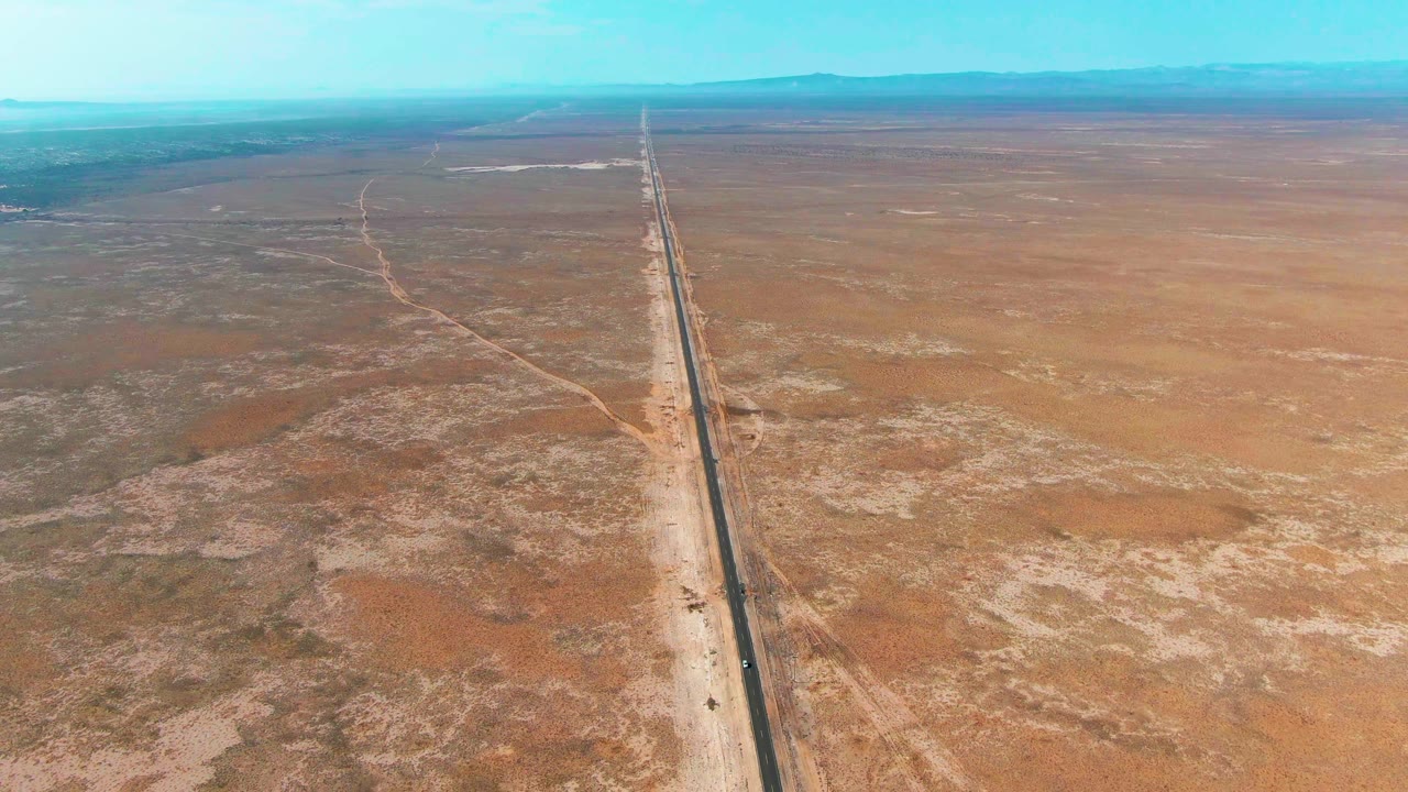 Aerial view of a straight highway crossing dry desert terrain.