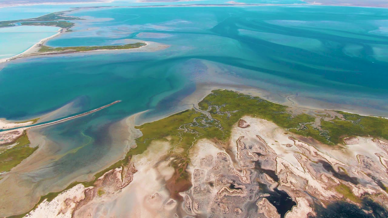 Aerial view of sandy tidal flats and green islands beside clear blue water.