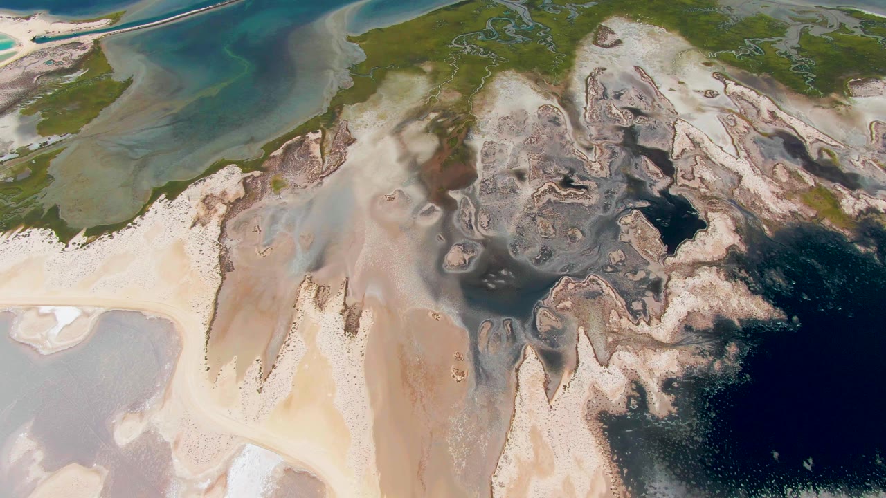 Aerial view of sandbars, shallow turquoise water, and dark mottled water