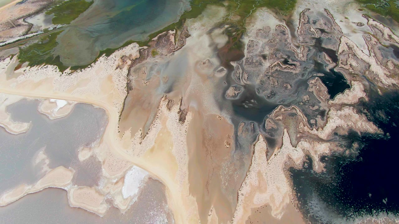 Aerial sandbar crossing between green water and dark tidal water
