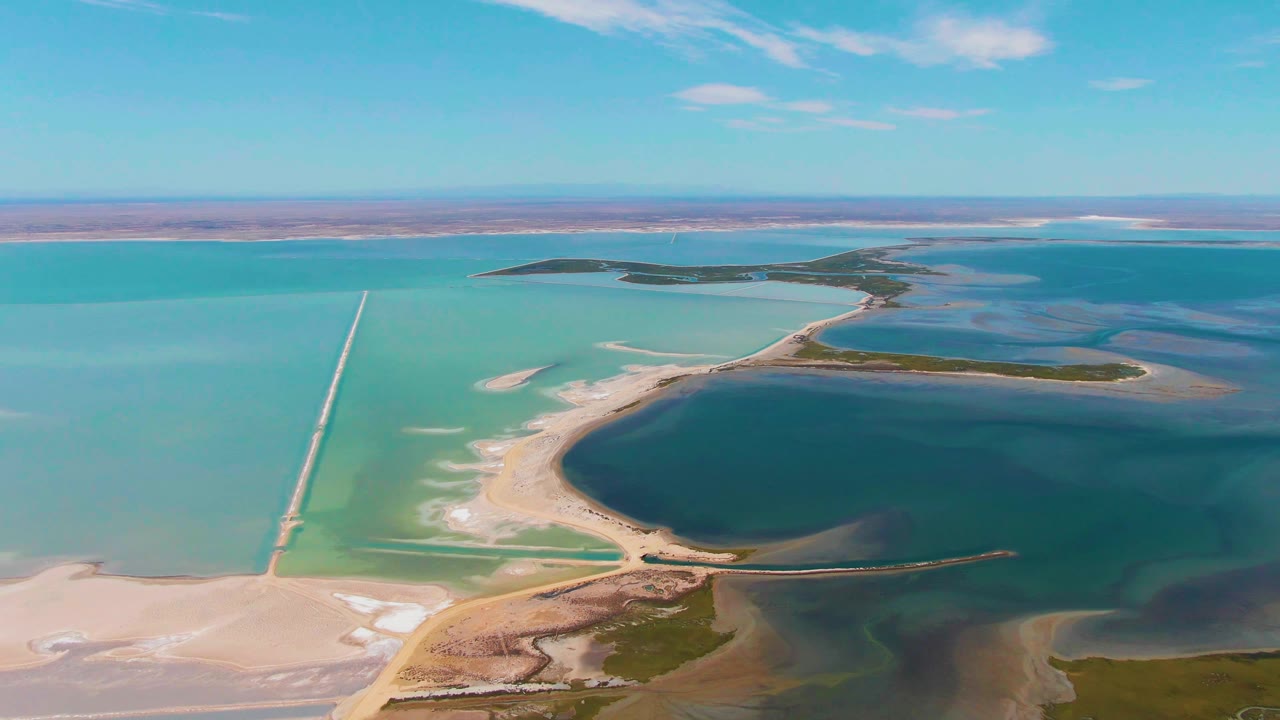 Aerial view of turquoise salt flat basins and sandy causeways.