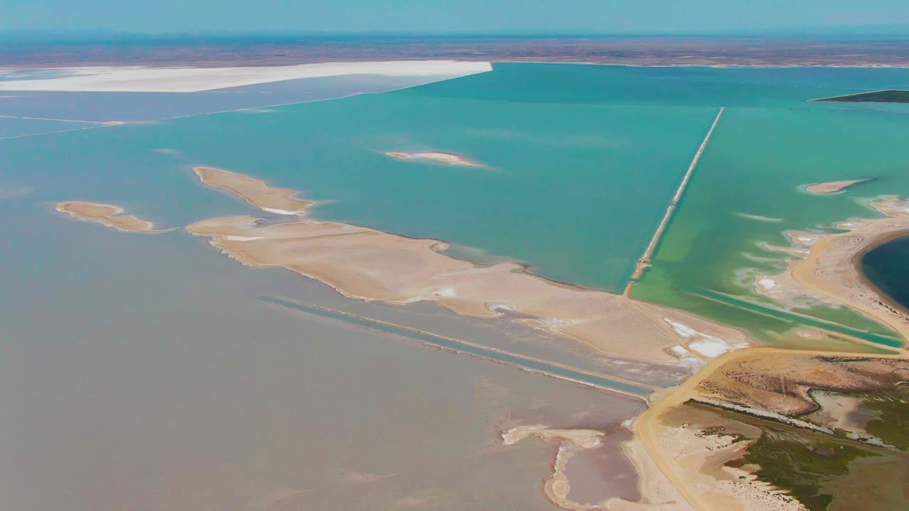 Aerial landscape with turquoise lagoon water, sand flats, and darker shoreline vegetation.