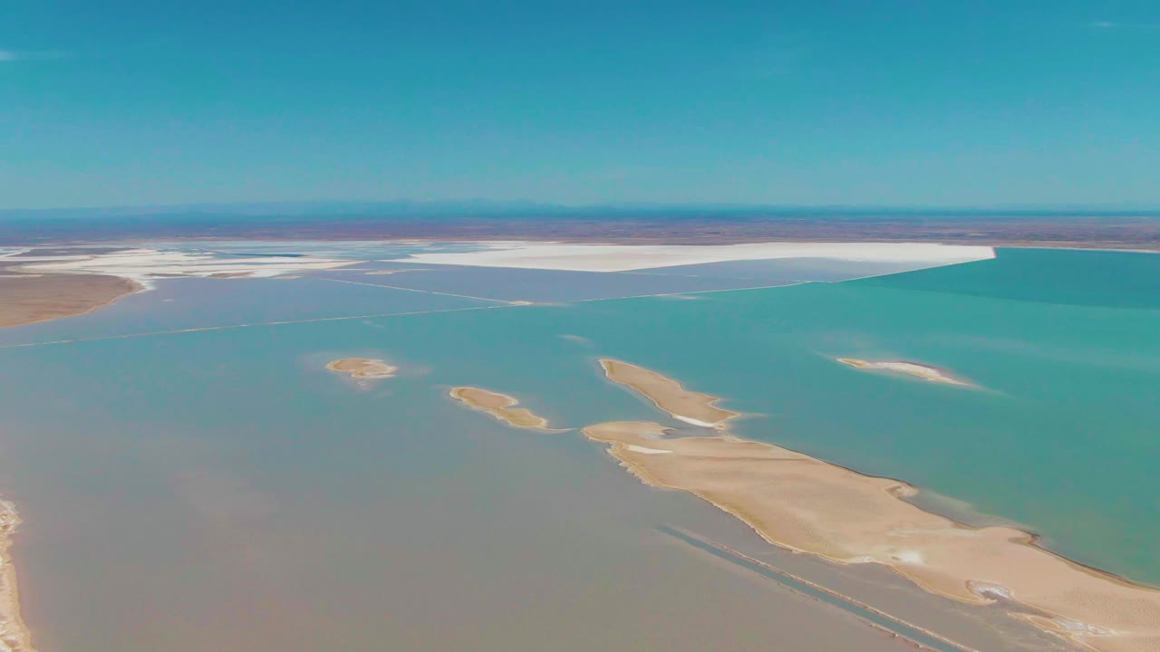 Aerial coastal landscape with turquoise water, pale islands, and distant white flats.