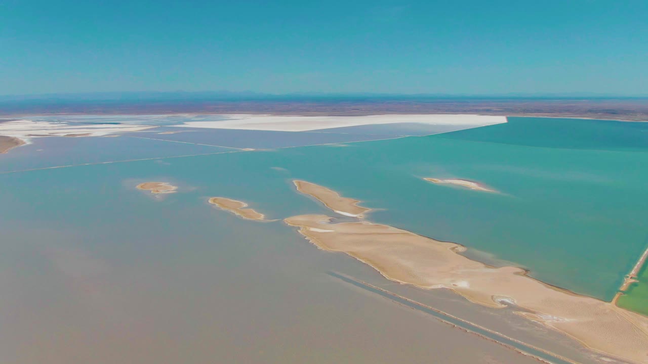 Turquoise evaporation pond bordered by pale salt flats and sandbars.