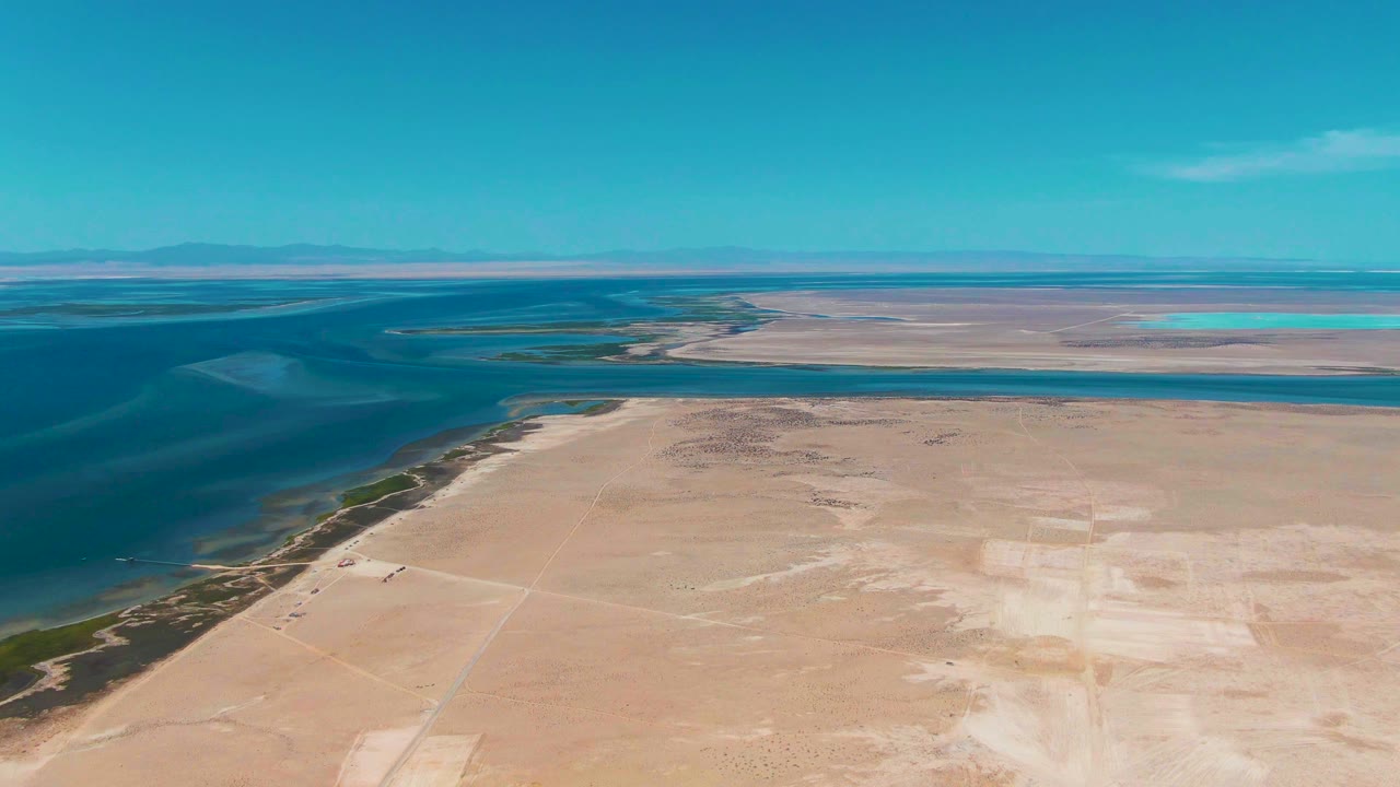 Elevated coastal landscape with sandy flats beside blue water.