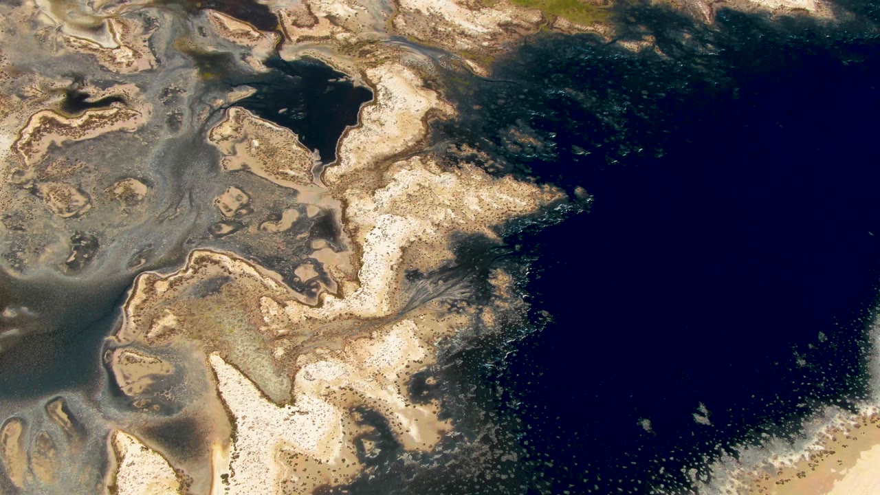 Overhead coastal water and pale sand patterns