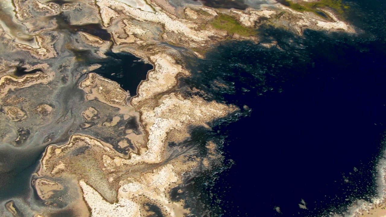 A high aerial frame in Guerrero Negro, Baja California Sur shows jagged pale shoreline forms reaching toward a broad dark water area, with no visible people.