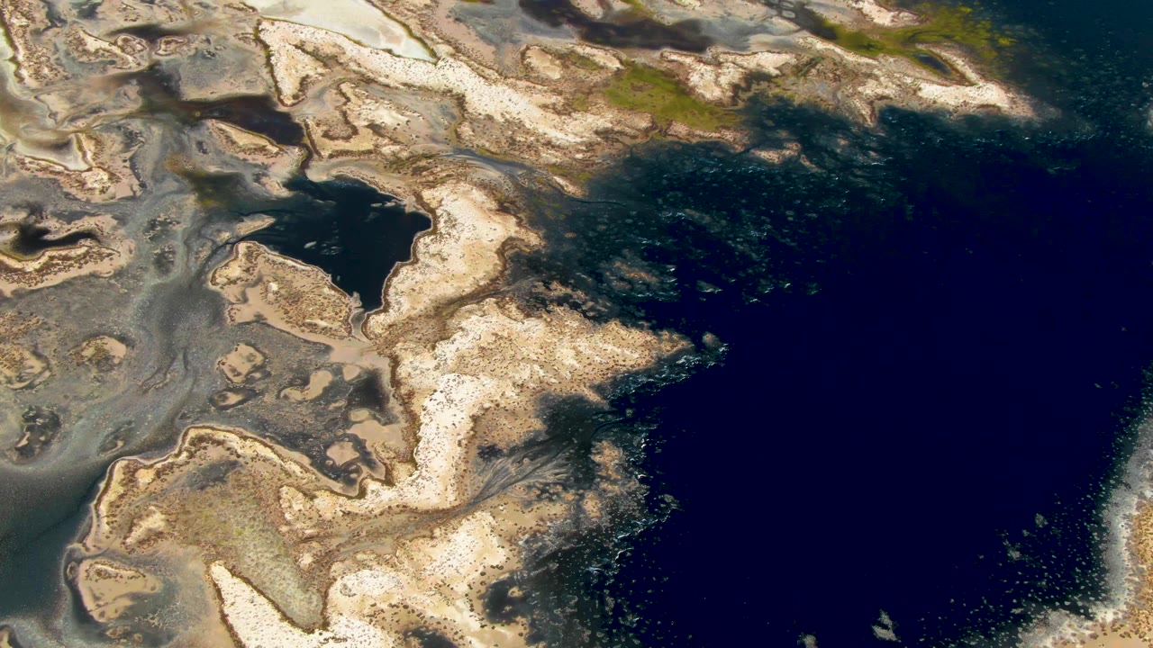 Overhead shoreline with gray pools and deep blue water.