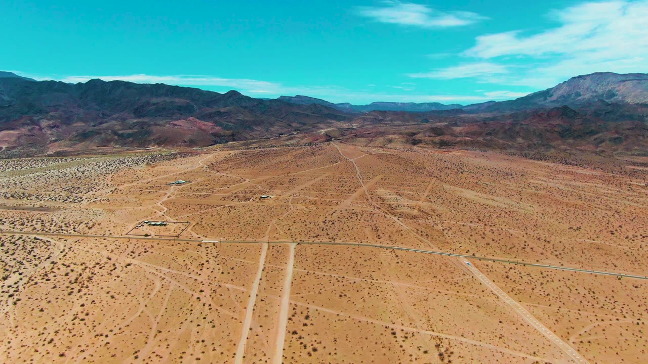 Aerial desert road with distant mountains and blue sky