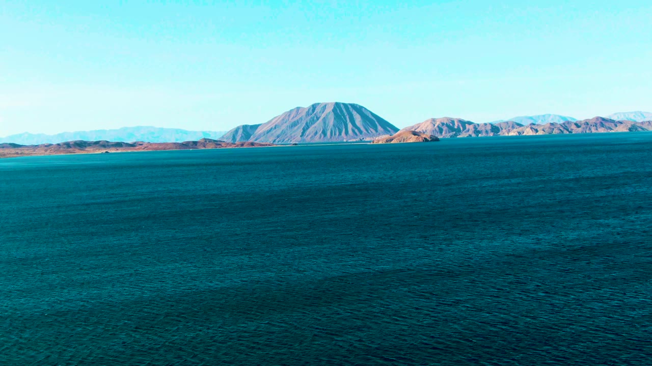 Open blue water facing a low mountainous shoreline.
