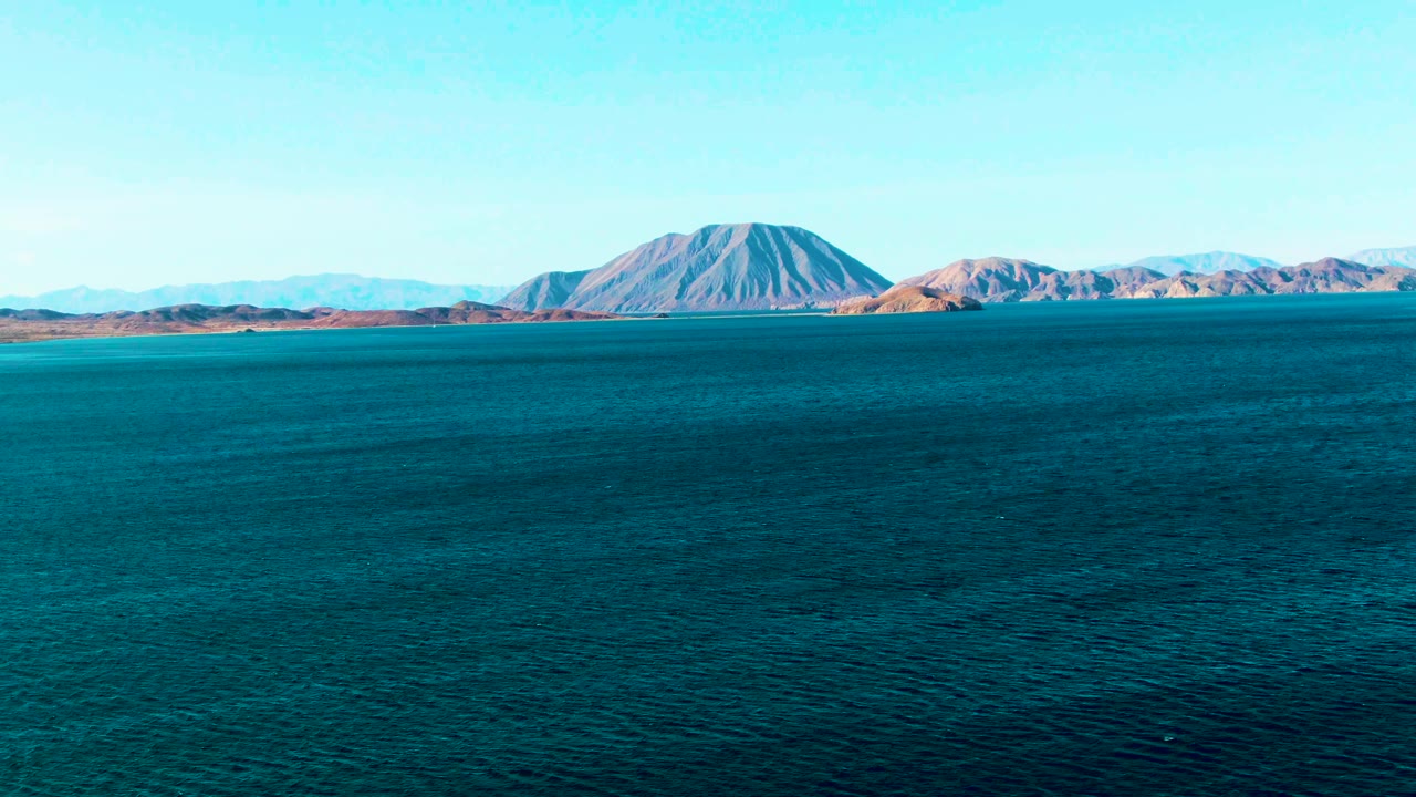 Distant island and low coastal hills beyond dark blue ocean
