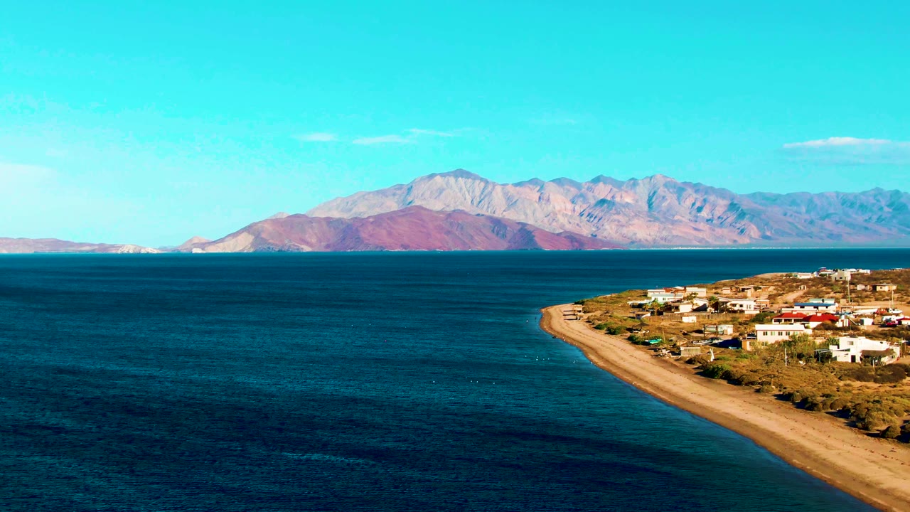 Aerial coastline view with open blue water and a small settlement along the shore.