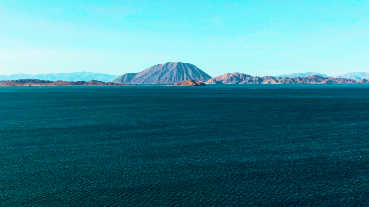Second frame of Bahia De Los Angeles with the mountain range centered beyond the rippled ocean surface and no visible people or vessels.