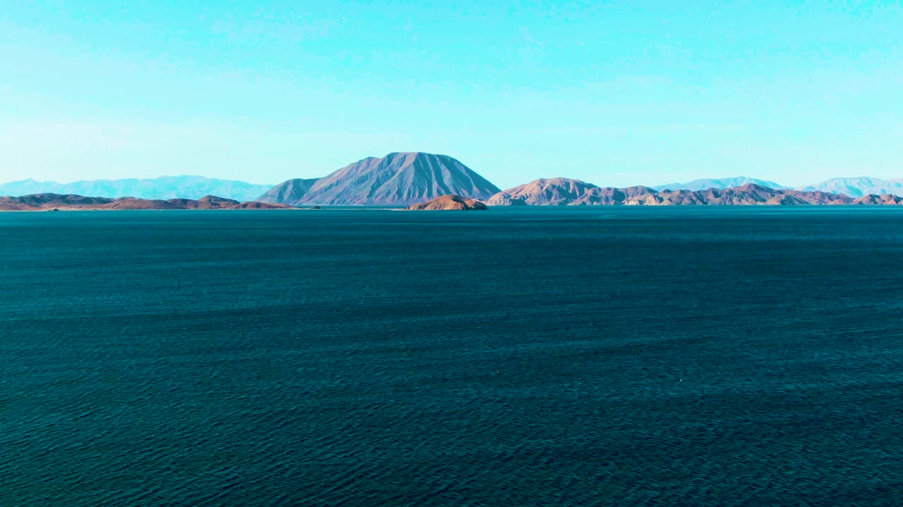 Distant desert-colored mountains beyond calm blue-green water