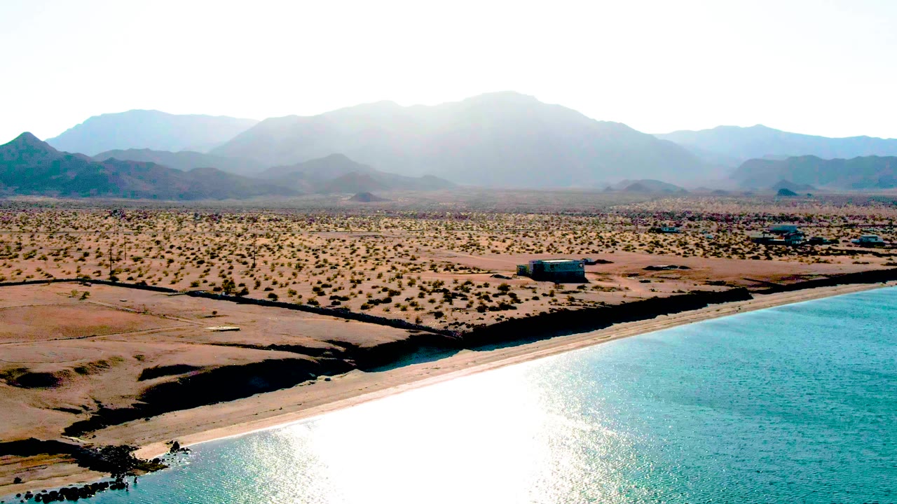 Turquoise bay water beside dry shoreline and mountain horizon