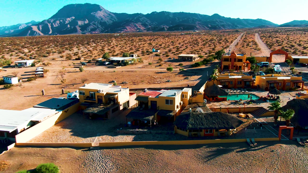 Aerial frame of buildings and pool beside open desert