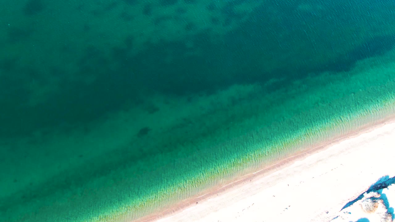 Clear green-blue water receding from sandy shore