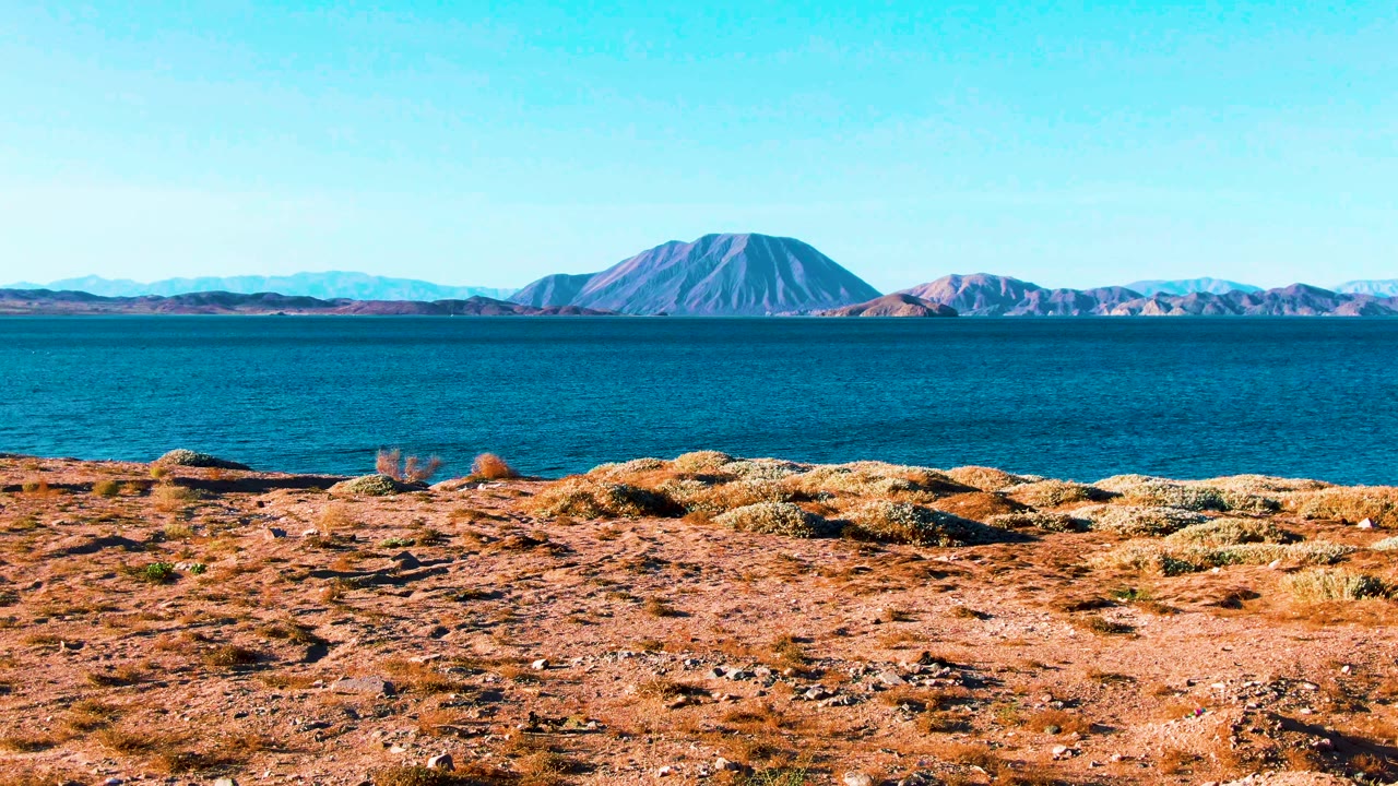 Rocky desert foreground facing calm water and far mountains