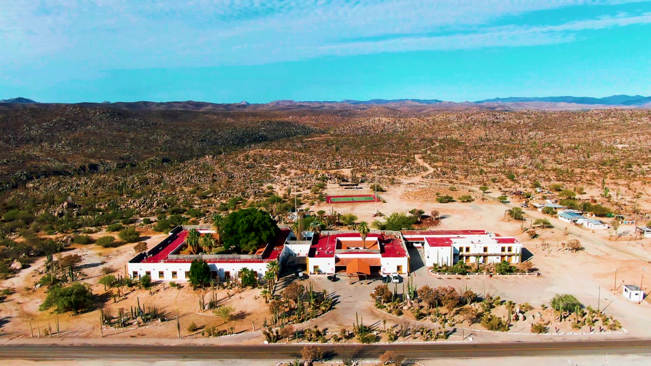 Aerial pass over Catavina desert buildings and mountain backdrop