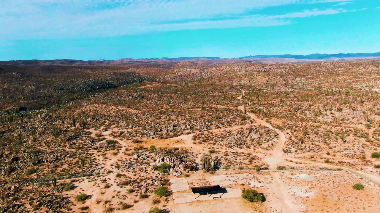 Rocky desert terrain with a dirt road and the court mostly out of frame.