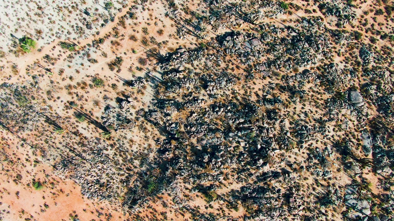 Dry desert ground with rock clusters and scrub vegetation