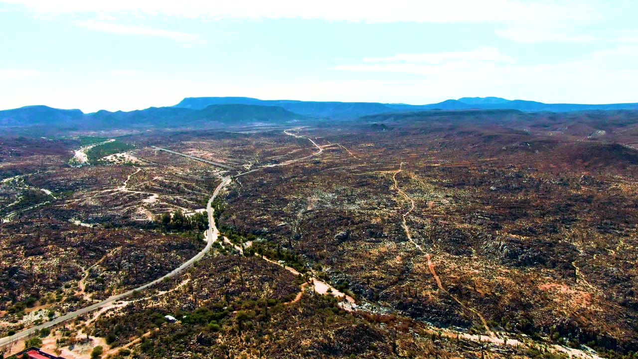 Desert road crossing hilly terrain under a clear sky
