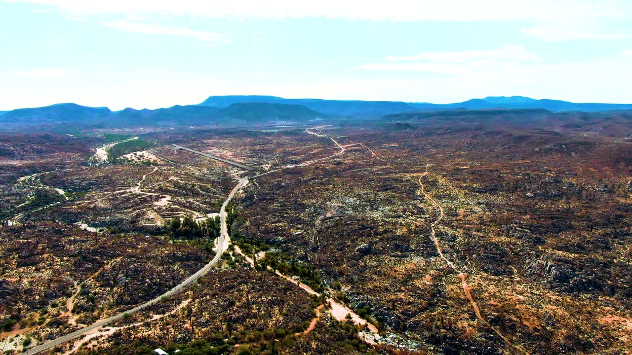 Aerial landscape of desert roads, scrub, and low mountains.
