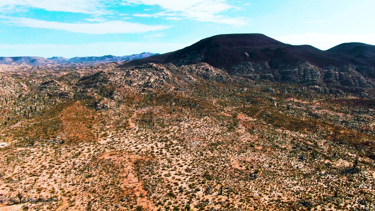 Elevated view across arid desert brush toward rocky hills and mountains.