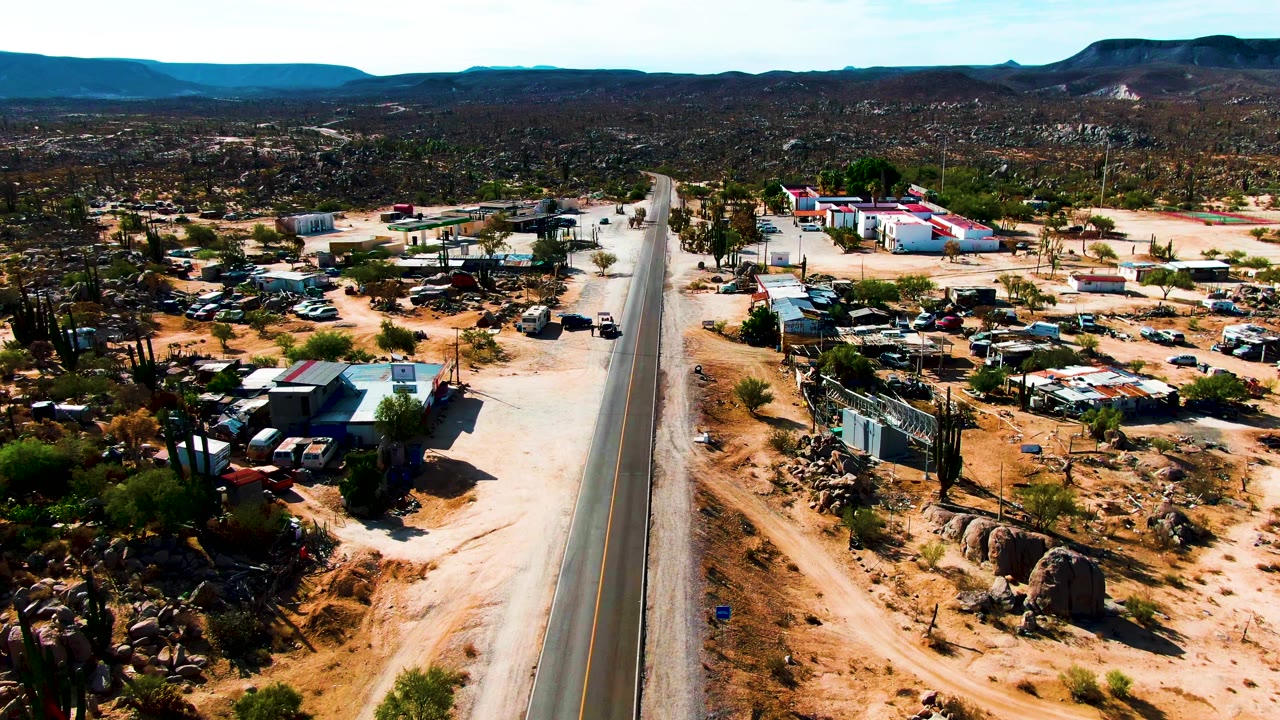 Centered road with sandy settlement lots and hills