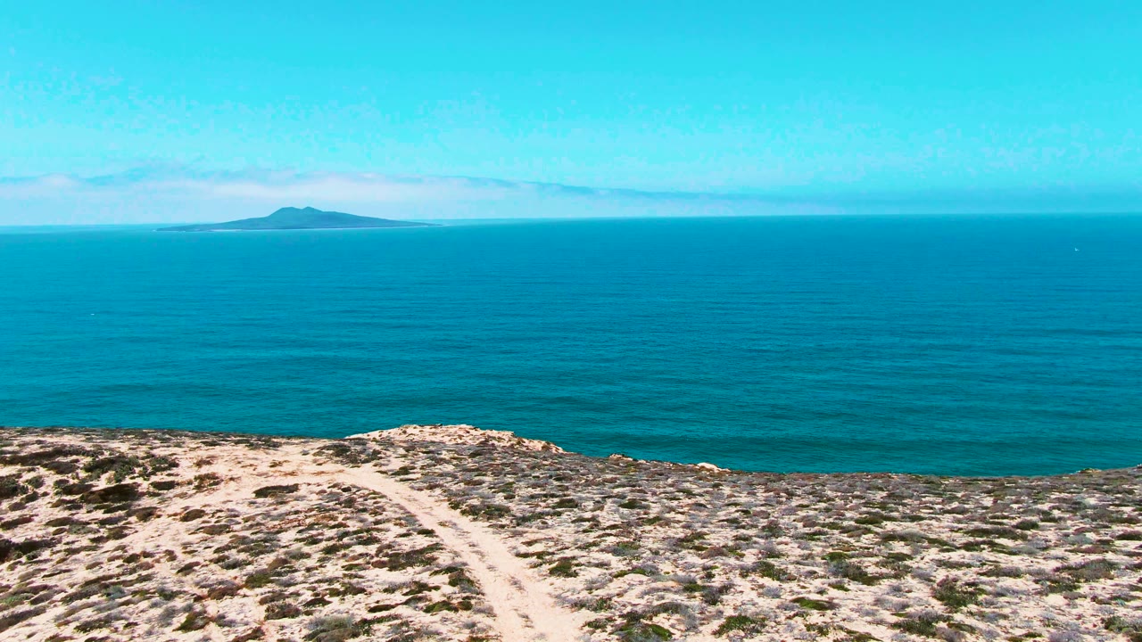 Wide ocean horizon beyond arid coastal hillside
