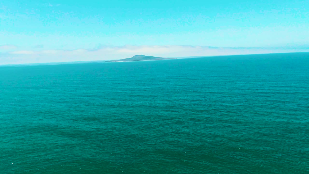 Distant island across a wide turquoise ocean horizon