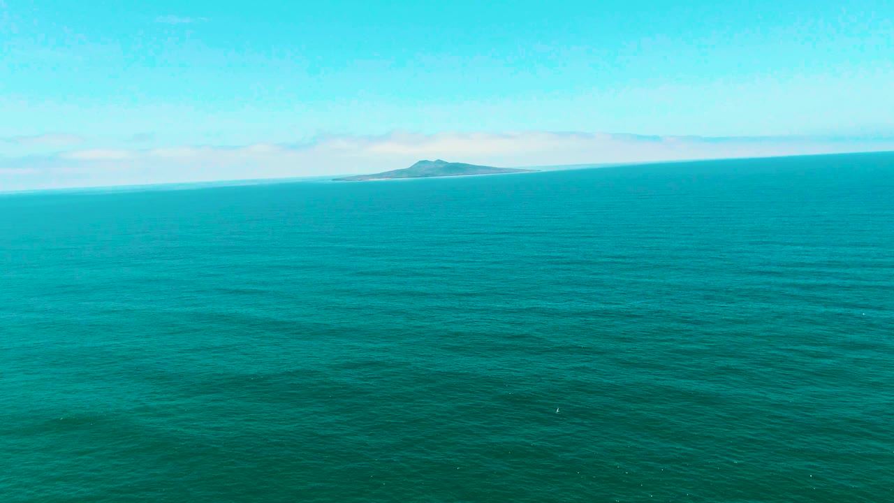 One second into the San Quintin BC, Mexico clip, the island remains small against the horizon while darker ripples texture the turquoise water, with no visible people.