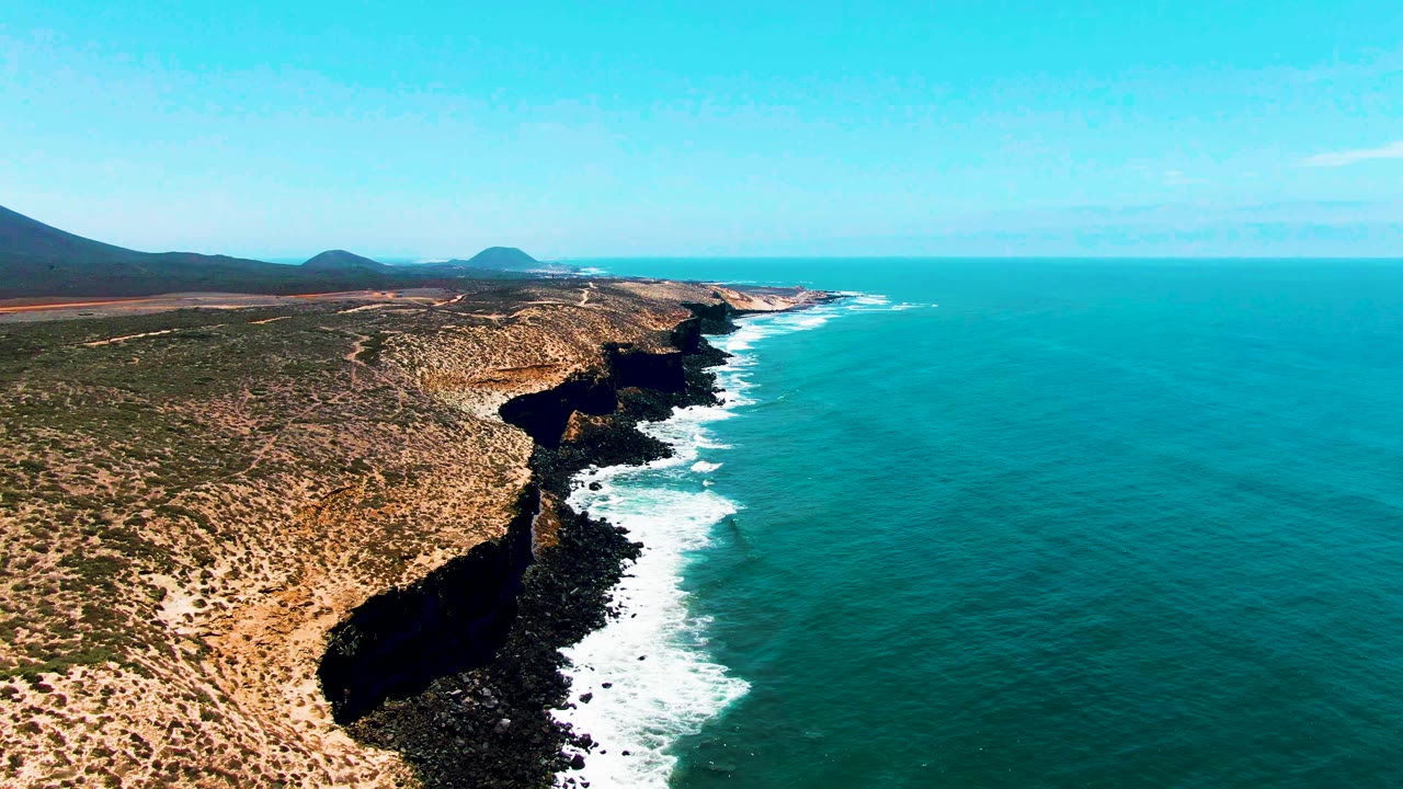 Aerial view of rocky coastline with waves breaking below cliffs