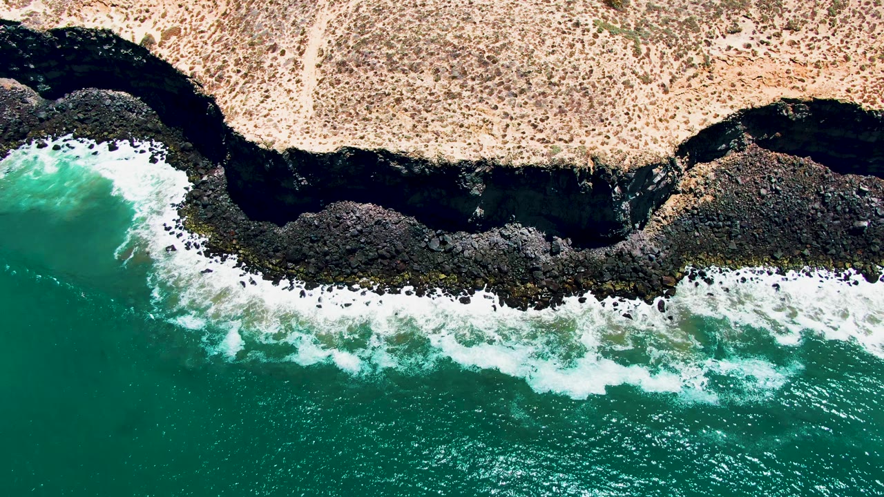 Rocky coastal shelf with foamy water rolling along the shore.