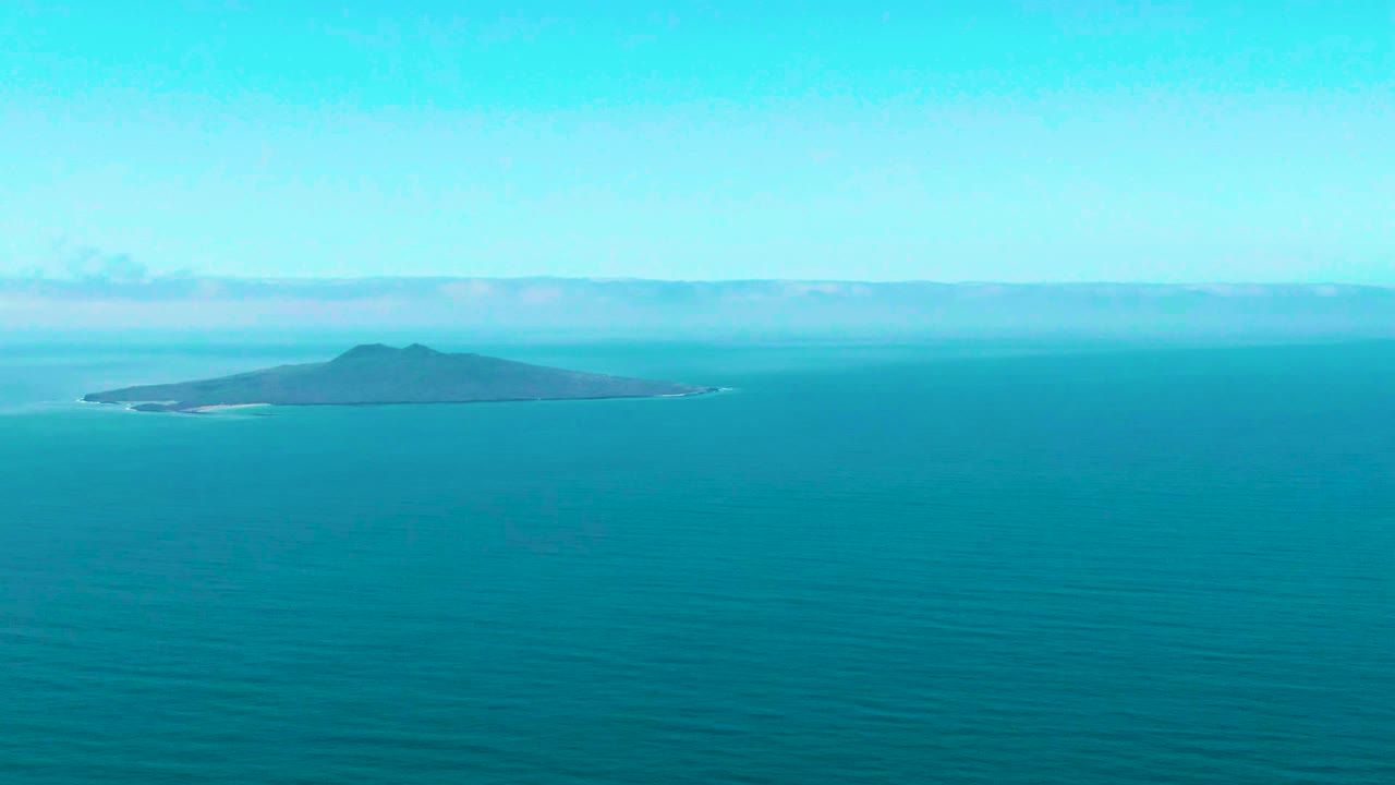 Third frame keeps the island near the upper center of the San Quintin BC ocean view, with a wide teal water foreground and no visible people.