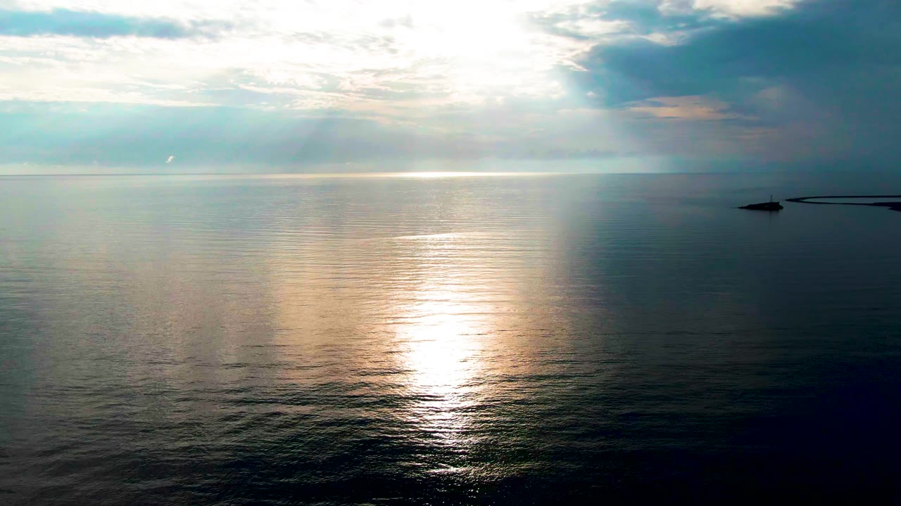 At two seconds, the ocean near Santa Rosalia remains calm while the sun reflection sits low and bright, framed by a high horizon and a shadowed cloud bank to the right, no visible people.