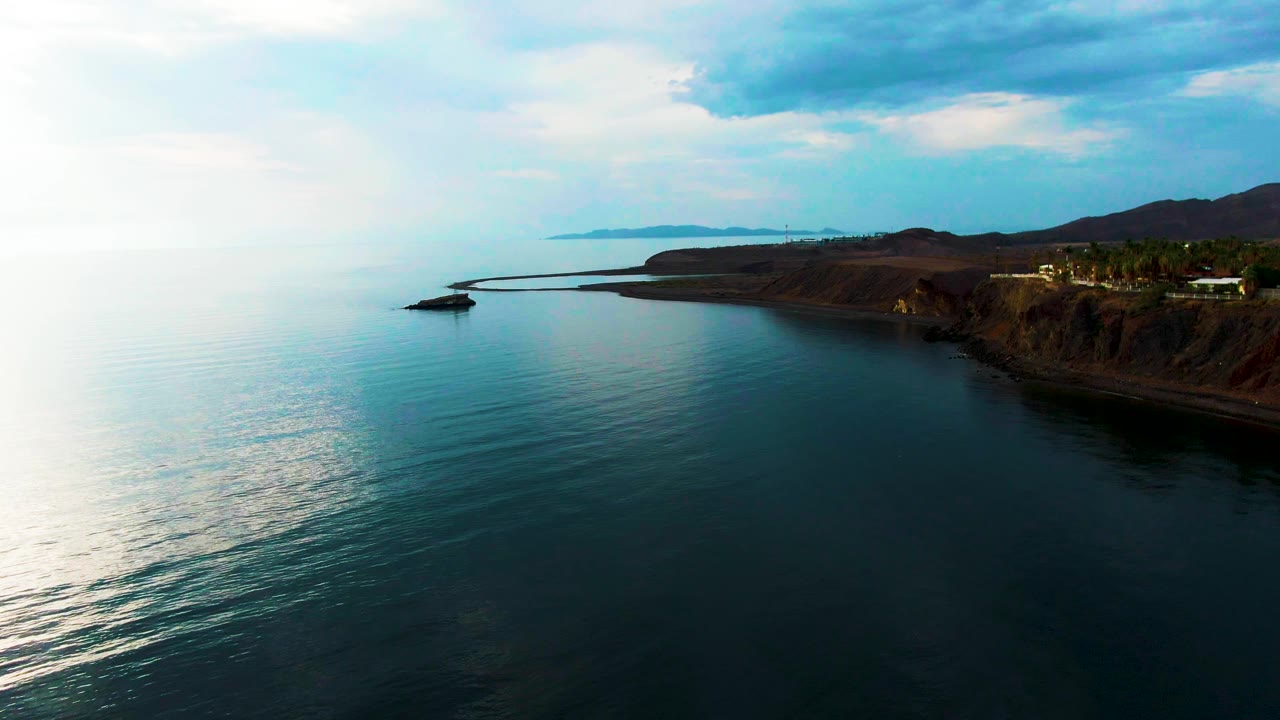 Blue green ocean ripples near a curved cliffside shore