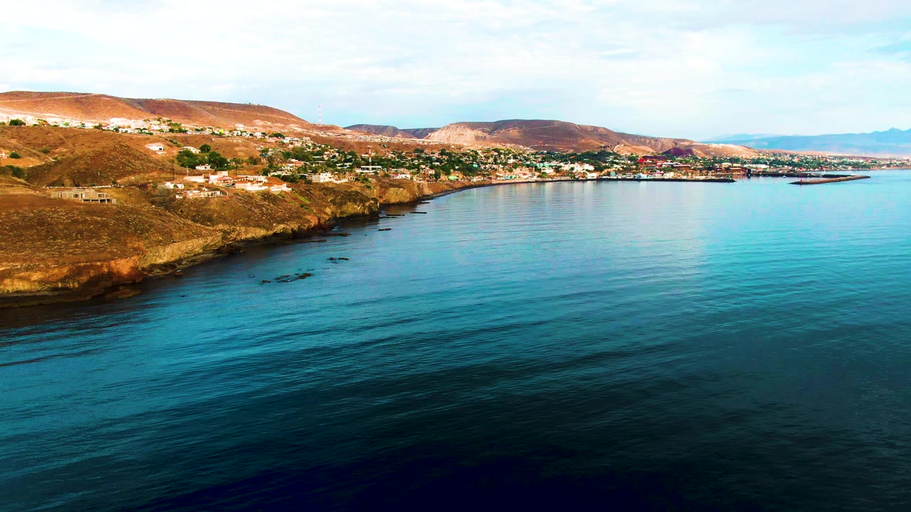 Low waves ripple across blue-green water near a rocky shore.