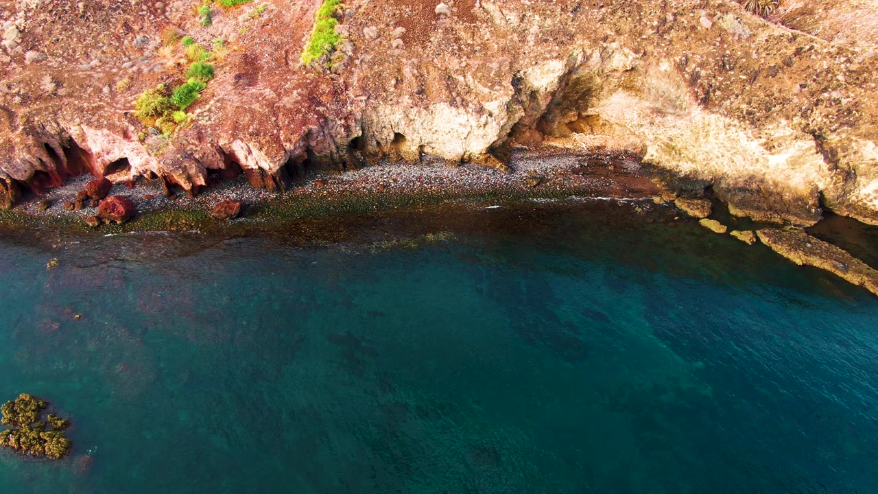 Overhead rocky coastline beside turquoise water.