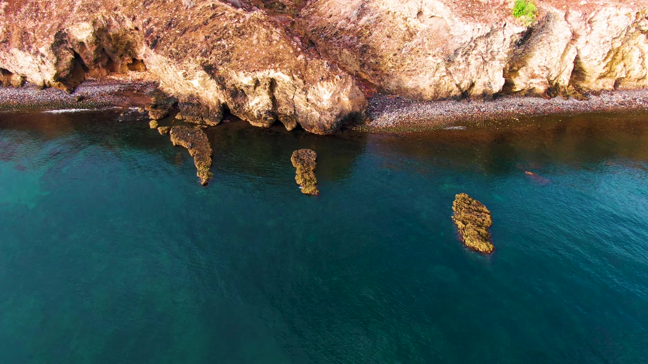 Overhead rocky shoreline above clear teal water