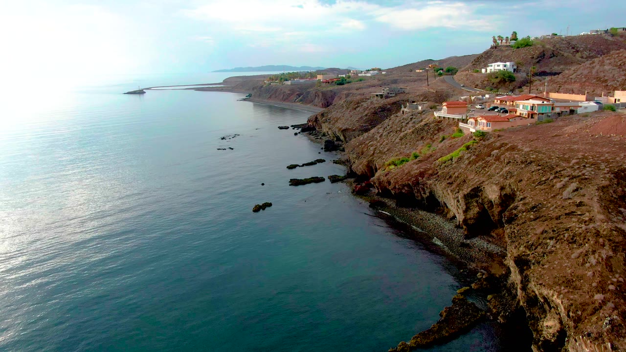 Rocky coastline with calm water and homes above the cliff edge.
