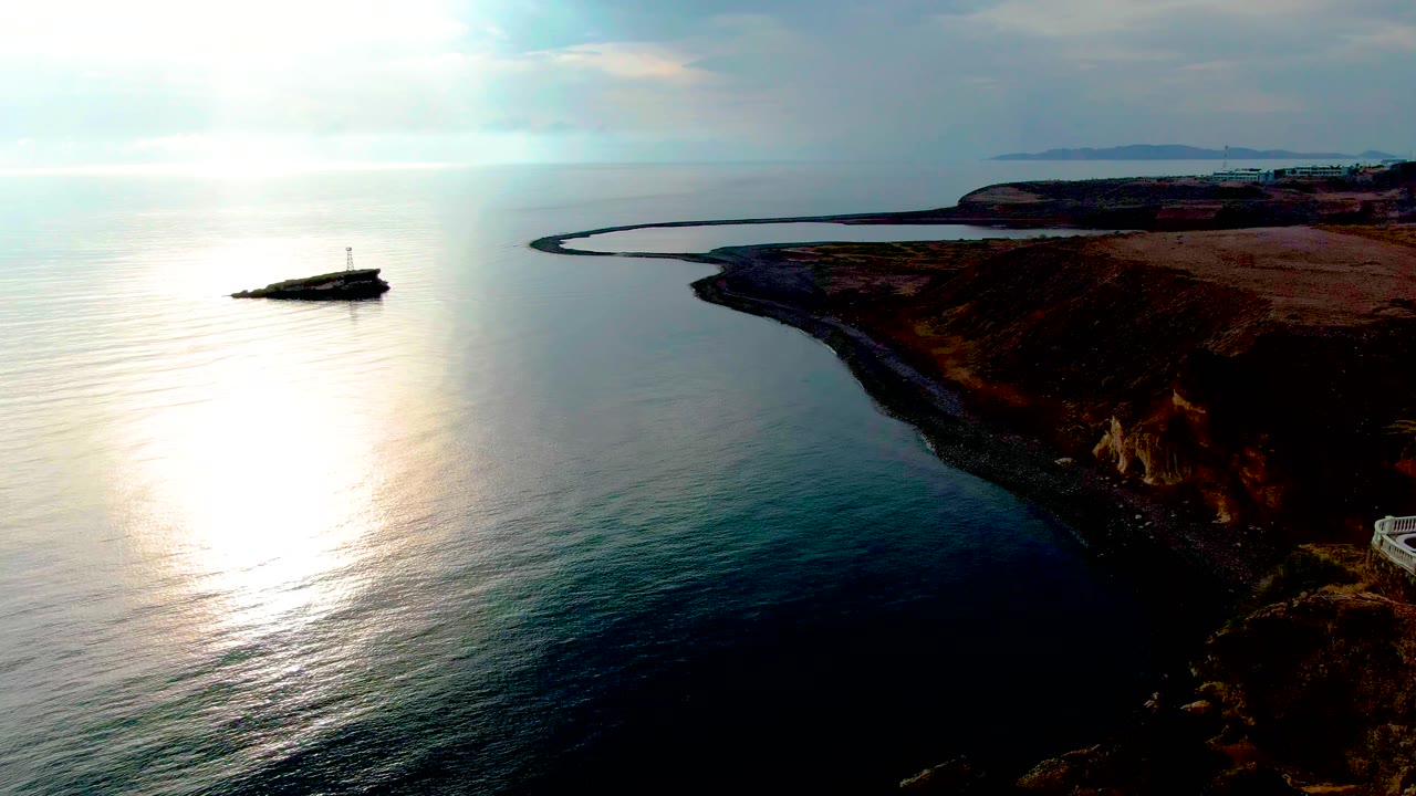 Bright ocean glare and curving rocky shoreline